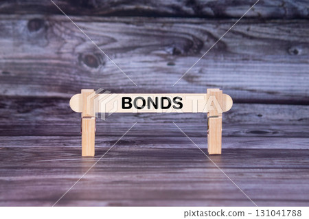 Bonds symbol. A wooden stick secured by Clothespins set over beautiful Realistic Wooden Texture Background. Business and Bonds concept with copy space 131041788