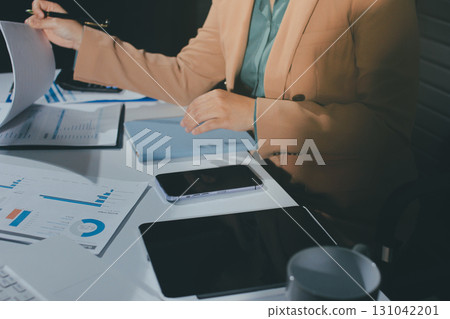 Close-up of businessman's hands making notes, mobiles, chart, desk, office 131042201