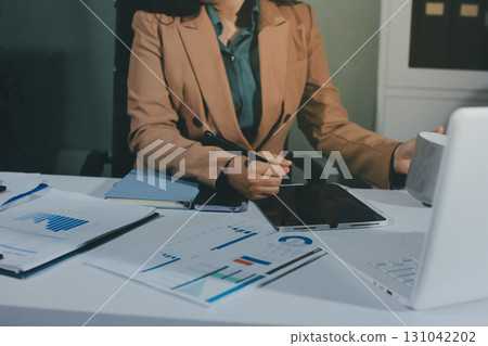Close-up of businessman's hands making notes, mobiles, chart, desk, office 131042202