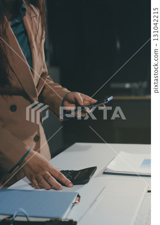Close-up of businessman's hands making notes, mobiles, chart, desk, office 131042215