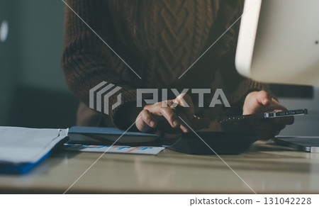 Close-up of businessman's hands making notes, mobiles, chart, desk, office 131042228