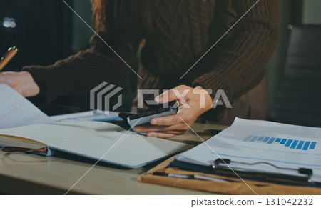 Close-up of businessman's hands making notes, mobiles, chart, desk, office Close-up of businessman's hands making notes, mobiles, chart, desk, office 131042232