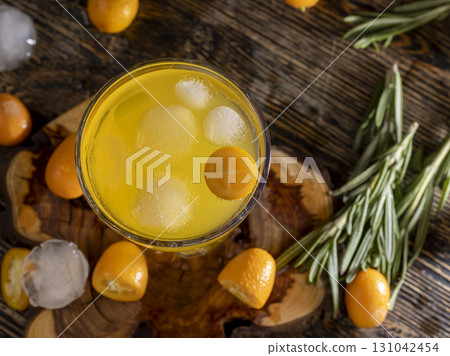 delicious and fresh orange juice and fresh kumquat fruits next to a glass, top, close up 131042454