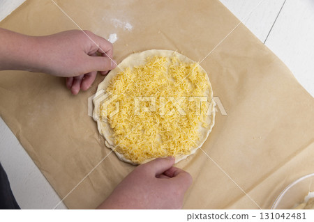 cheese tortilla made of dough and grated cheese, thinly rolled yeast dough sprinkled with yellow hard grated cheese 131042481
