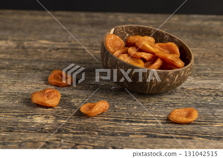 orange dried apricots made from ripe apricots in a coconut shell plate, dried apricots in a bowl made from natural materials orange dried apricots made from ripe apricots in a coconut shell plate, dried apricots in a bowl made from natural materials 131042515