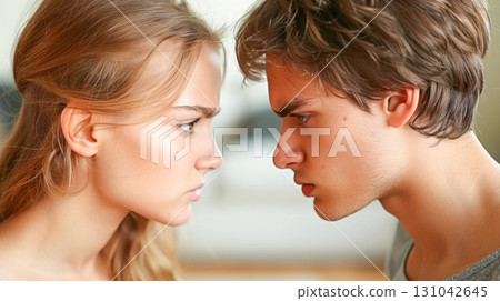 Intense gaze between young couple showcasing emotional connection and tension in a soft-lit environment 131042645