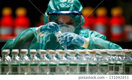 Medical professional in protective gear preparing vaccine vials in a laboratory setting with colorful background 131042851