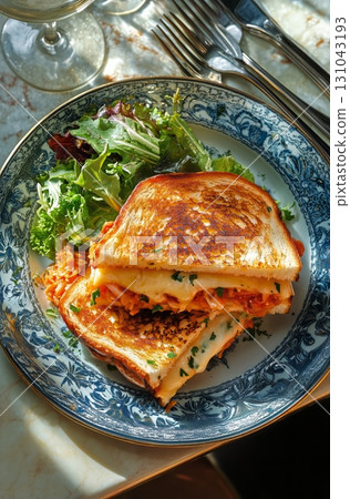 Grilled Cheese Sandwich With Marinara Sauce and Fresh Salad on a Blue Plate at a Cozy Dining Table. Grilled Cheese Sandwich With Marinara Sauce and Fresh Salad on a Blue Plate at a Cozy Dining Table. 131043193