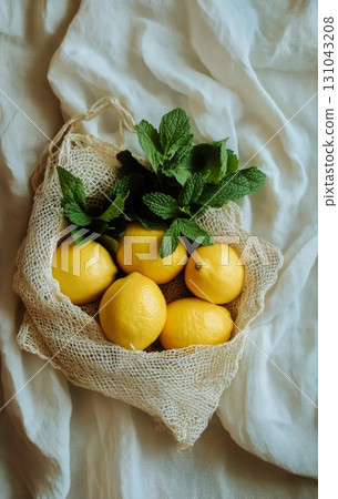 Fresh Lemons and Mint Leaves Arranged in a Natural Basket on a Dark Fabric Surface. Fresh Lemons and Mint Leaves Arranged in a Natural Basket on a Dark Fabric Surface. 131043208