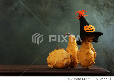 Pumpkins on table. Funny spider hat is on pumpkin. There are several pumpkins on table. Halloween holiday. Copy space. Pumpkins on table. Funny spider hat is on pumpkin. There are several pumpkins on table. Halloween holiday. Copy space. 131043301