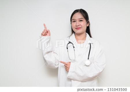 Portrait of Southeast Asian healthcare worker woman doctor in lab coat pointing finger up Portrait of Southeast Asian healthcare worker woman doctor in lab coat pointing finger up 131043500