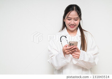 Portrait of Southeast Asian healthcare worker woman doctor in lab coat using mobile phone 131043514