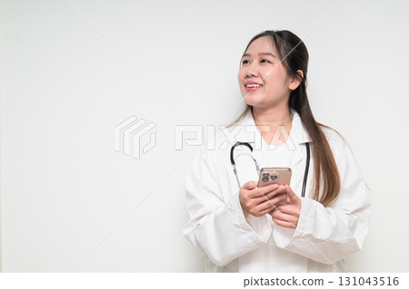 Portrait of Southeast Asian healthcare worker woman doctor in lab coat using mobile phone 131043516