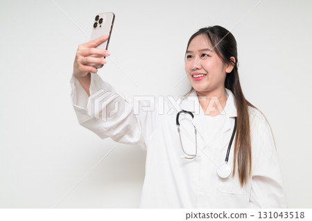 Portrait of Southeast Asian healthcare worker woman doctor in lab coat using mobile phone 131043518