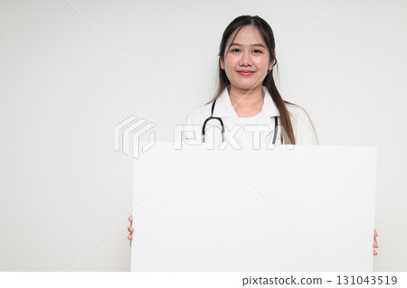 Portrait of Southeast Asian healthcare worker woman doctor in lab coat showing empty white board Portrait of Southeast Asian healthcare worker woman doctor in lab coat showing empty white board 131043519