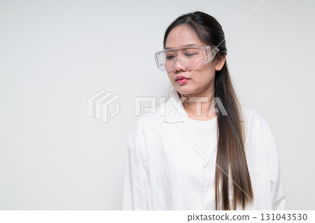 Asian healthcare worker scientist woman in lab coat wearing safety goggle glasses thinking Asian healthcare worker scientist woman in lab coat wearing safety goggle glasses thinking 131043530