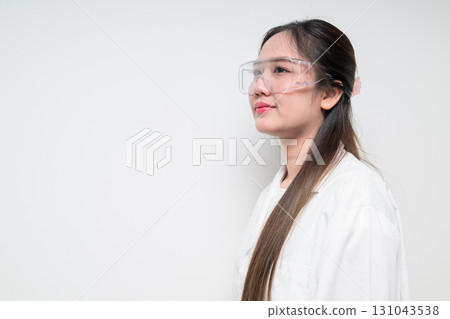Profile view of Asian healthcare worker scientist woman in lab coat wearing safety goggle glasses 131043538