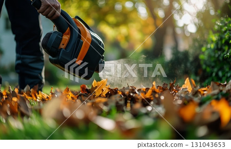 Autumn Cleanup With a Leaf Blower in a Sunny Garden. Autumn Cleanup With a Leaf Blower in a Sunny Garden. 131043653