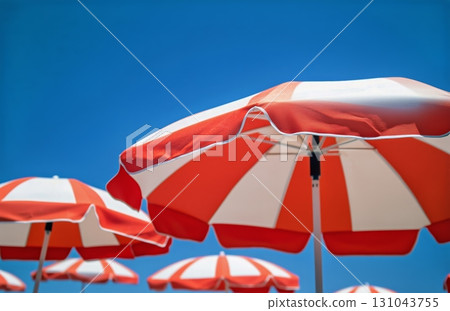 Bright Red and White Striped Umbrellas Against a Clear Blue Sky on a Sunny Day. Bright Red and White Striped Umbrellas Against a Clear Blue Sky on a Sunny Day. 131043755
