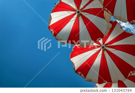 Bright Red and White Beach Umbrellas Against a Clear Blue Sky on a Sunny Summer Day 131043784