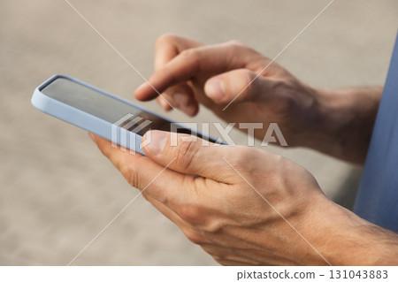 Man using and texting mobile phone. Check apps, focused on device, chatting or browsing internet. Online. Outdoors. 131043883