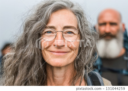 Mature woman with glasses smiling warmly, showcasing natural beauty and confidence in outdoor setting Mature woman with glasses smiling warmly, showcasing natural beauty and confidence in outdoor setting 131044259