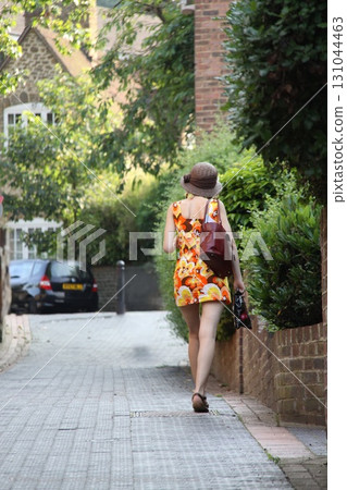 A woman in a 1950s-style dress walks down the street 131044463