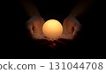 Luminous glowing sphere nestled in cupped hands, radiating warmth and potential against shadowy background, representing innovative thinking and human connection 131044708