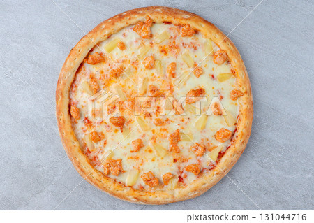 Hawaiian Style Pizza with Chicken, Pineapple, and Melted Cheese on Crispy Crust over Gray Stone Background Hawaiian Style Pizza with Chicken, Pineapple, and Melted Cheese on Crispy Crust over Gray Stone Background 131044716