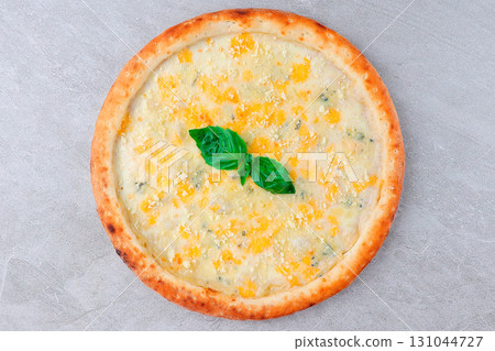 Four Cheese Pizza with Mozzarella, Parmesan, Blue Cheese, and Basil on Golden Crust over Gray Stone Background 131044727
