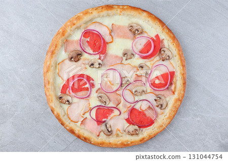 Pizza with Chicken, Mushrooms, Red Onion Rings, Tomato Slices, and Melted Cheese on Gray Stone Background 131044754