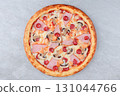 Classic Pizza with Ham, Mushrooms, Pepperoni, Chicken, and Melted Cheese on Baked Crust over Gray Stone Background 131044766
