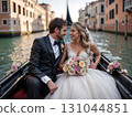 Happy couple in wedding attire smiling in Venetian gondola at dusk. Ideal for romance-themed content, luxury travel ads, and wedding inspiration. Radiates joy and intimacy 131044851