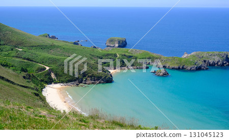An idyllic high-angle shot captures the secluded, sandy Torimbia beach with calm turquoise waters in Asturias, Spain. An idyllic high-angle shot captures the secluded, sandy Torimbia beach with calm turquoise waters in Asturias, Spain. 131045123