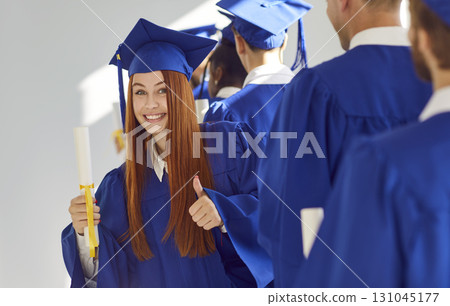 Young smiling joyful girl student in a university graduate gown and diploma in her hands. 131045177