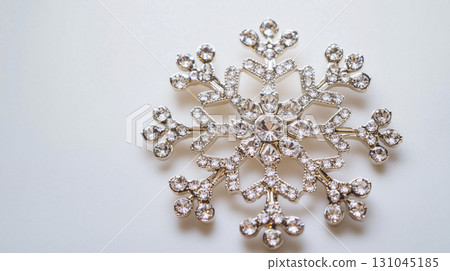 Top-down view of a gleaming silver snowflake brooch 131045185