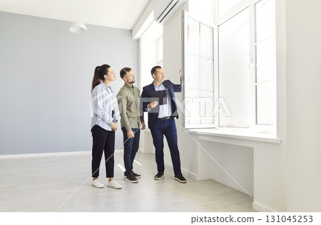A couple and an agent view an empty house 131045253