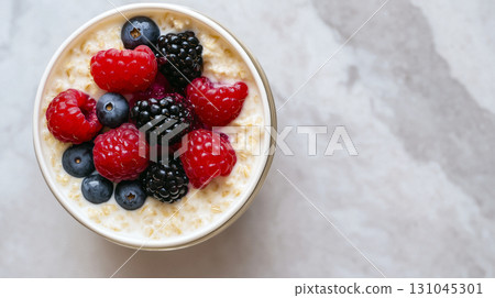 Creamy oatmeal bowl topped with vibrant berry jam and fresh fruit 131045301