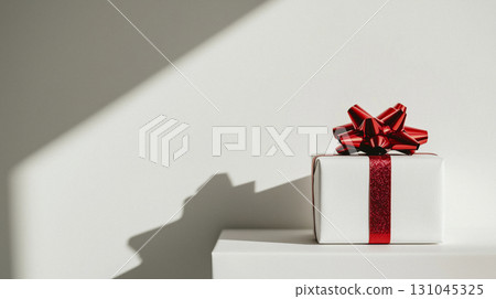Elegant white gift box adorned with a vibrant red twisted rope bow 131045325