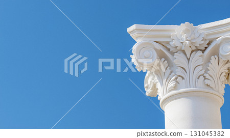 Ornate white stone column capital set against a brilliant azure sky 131045382
