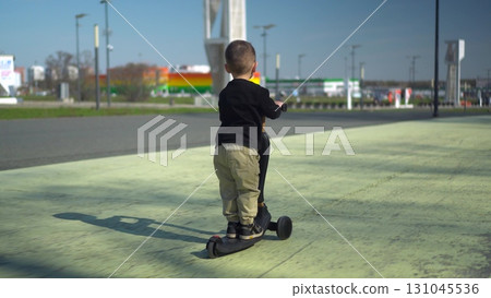 A Happy Child Riding a Bright Scooter in the Open Park, Enjoying an Adventurous Day A Happy Child Riding a Bright Scooter in the Open Park, Enjoying an Adventurous Day 131045536