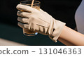 Blank suede gloves worn mockup, hand holding iced coffee, isolated close-up 131046363