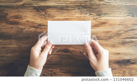 Hands holding a white piece of paper 131046602