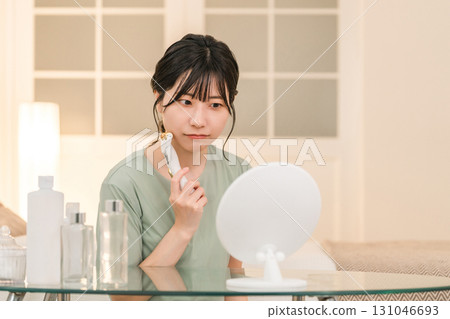 亞洲女性晚上在臥室用臉部滾輪按摩 131046693