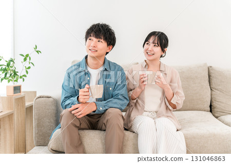 年輕夫婦在沙發上喝著熱飲放鬆 131046863