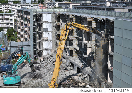 Aged public housing to be demolished Work scene of dismantling with large heavy machinery 131048359