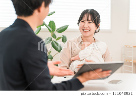 一位母親抱著嬰兒,在上門推銷時聽取推銷員的建議,一位女性顧客 一位母親抱著嬰兒,在上門推銷時聽取推銷員的建議,一位女性顧客 131048921
