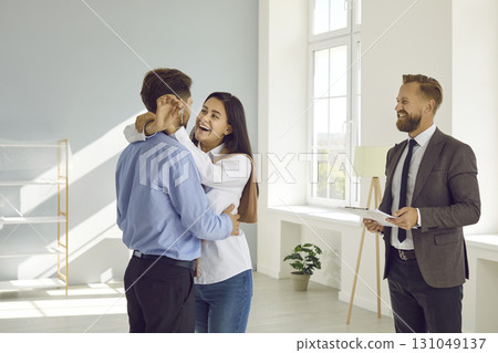 Happy joyful young couple buying a new house or apartment, having fun and hugging 131049137