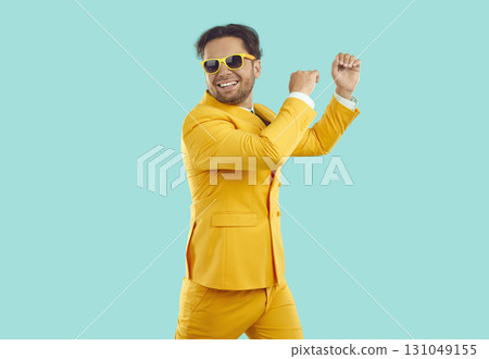 Portrait of happy funny guy in yellow suit and sunglasses dancing on turquoise background. Portrait of happy funny guy in yellow suit and sunglasses dancing on turquoise background. 131049155