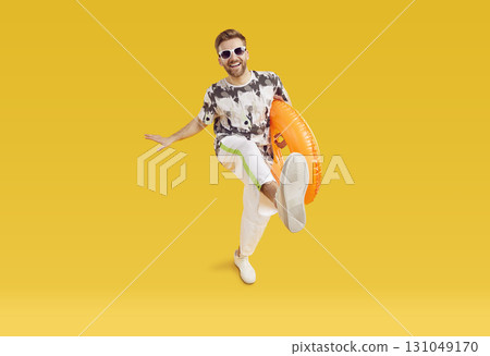 Funny man in sunglasses holding rubber ring and having fun isolated on studio yellow background. 131049170